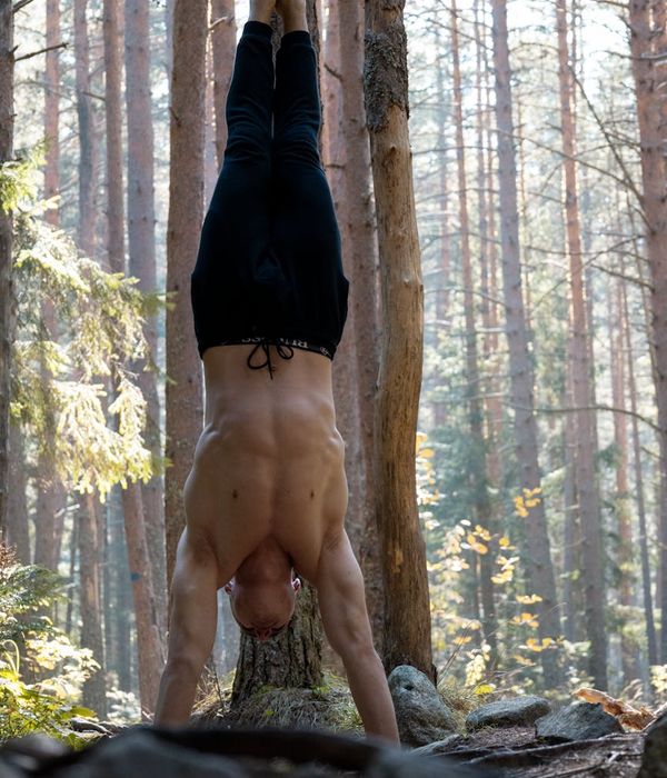 Man in a focused state during a complex bodyweight exercise, showing muscle definition.